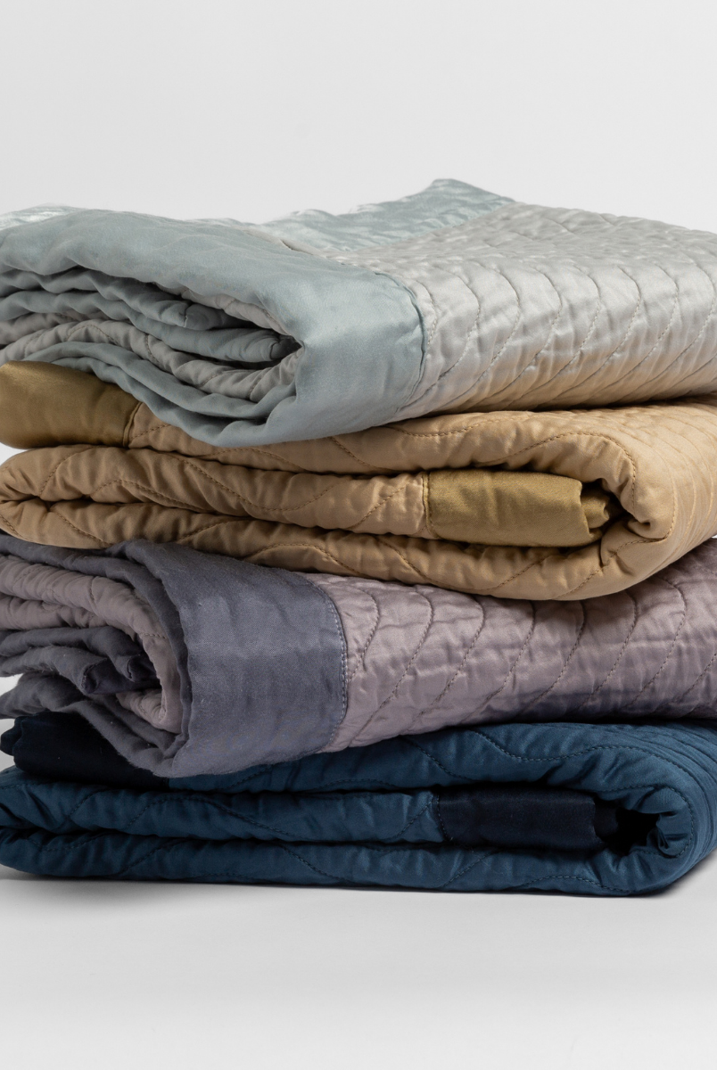 [allvariants]: stack of 4 quilted cotton sateen baby blankets in cloud, honeycomb, French Lavender and Midnight.
