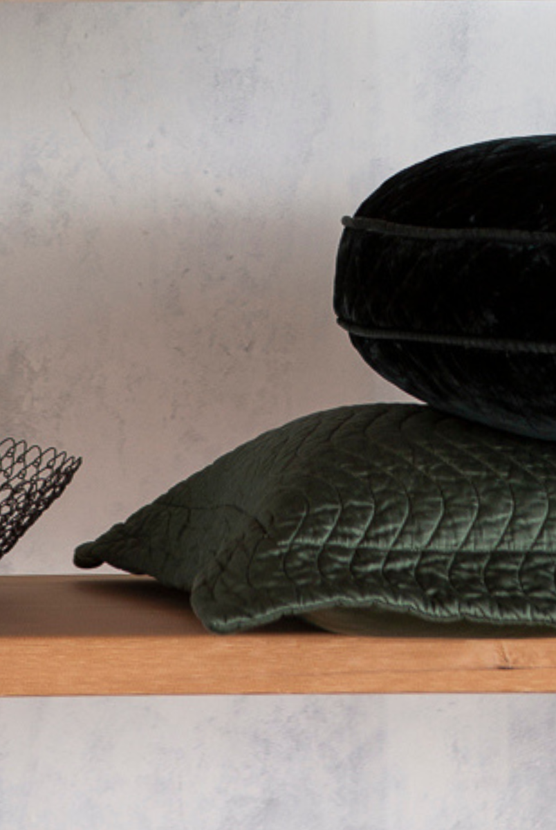 [allvariants]: quilted throw pillows in silk velvet and cotton sateen in juniper, a deep green on a shelf with a wire bowl. 