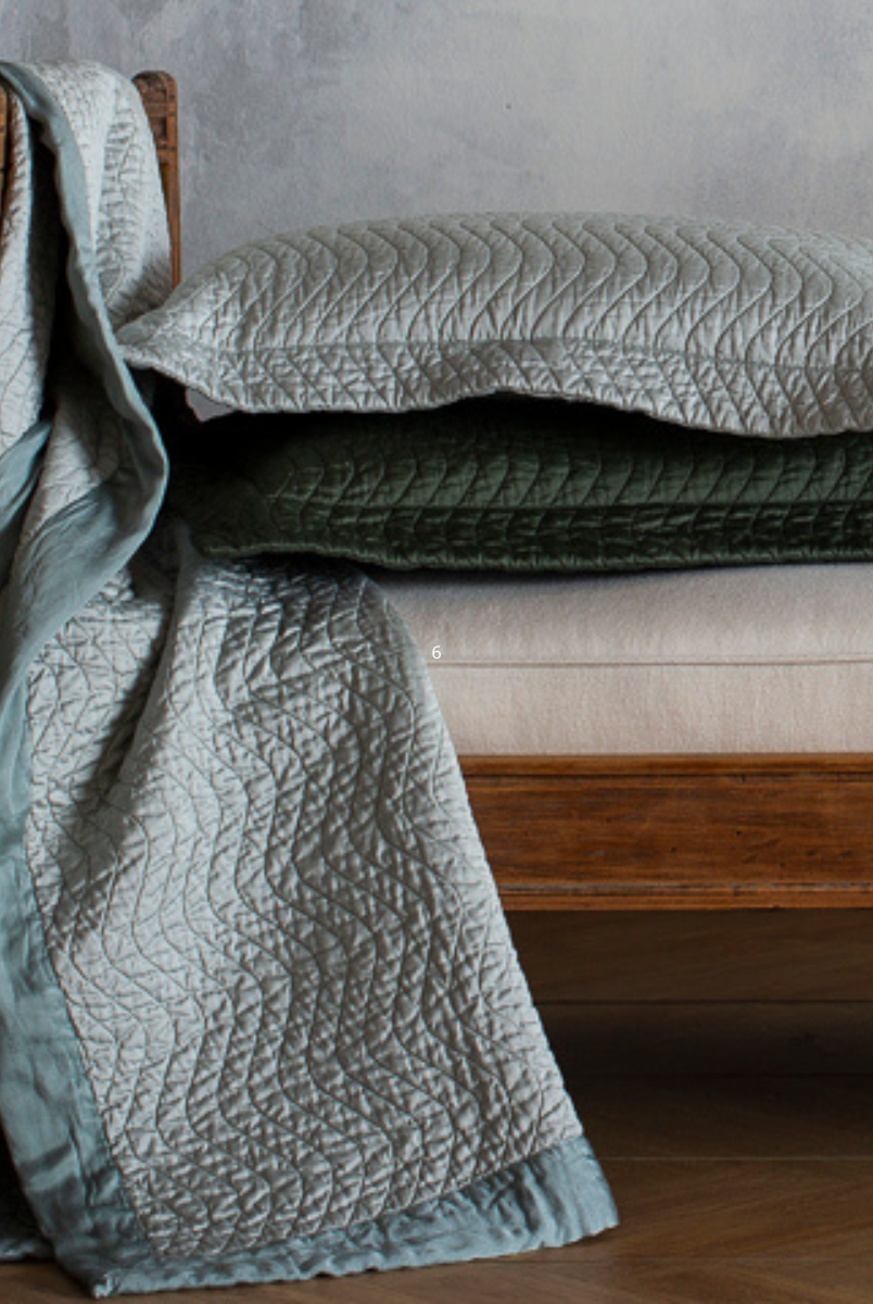 [allvariants]: throw blanket and throw pillows in quilted cotton sateen shown on the end of a daybed - the pillows are stacked and the blanket draped over the side. 
