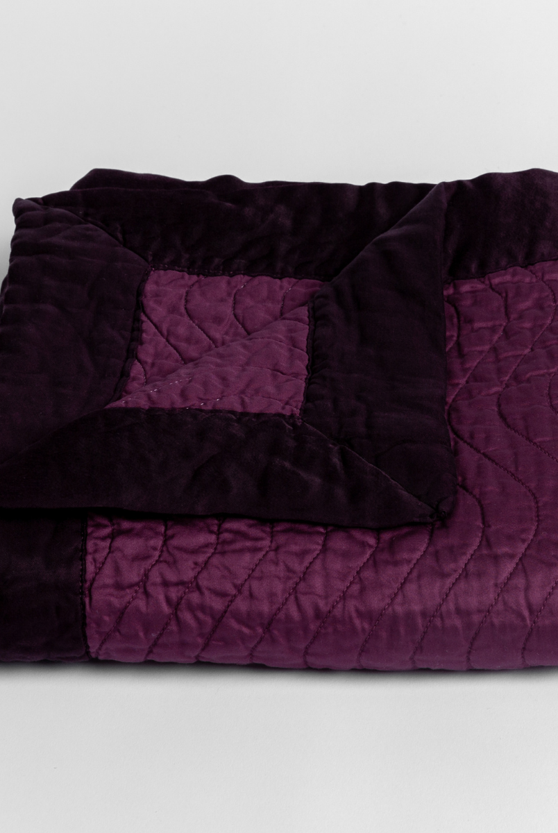 Fig: a folded quilted cotton sateen baby blanket with its corner folded down to show the trim contrast - shot against a white background. 
