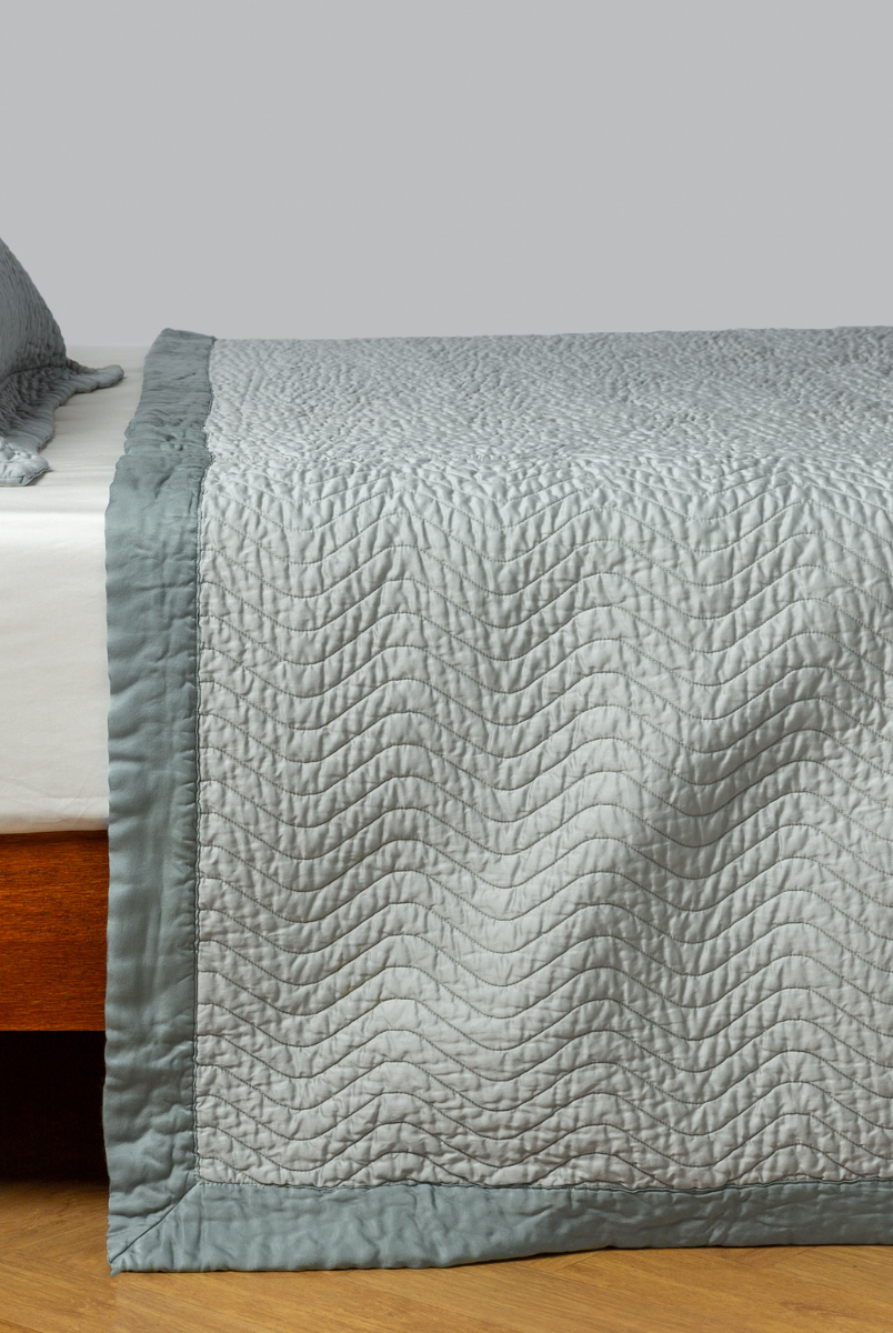 Eucalyptus: quilted cotton sateen coverlet with matching sham on a winter white fitted sheet - side view. 