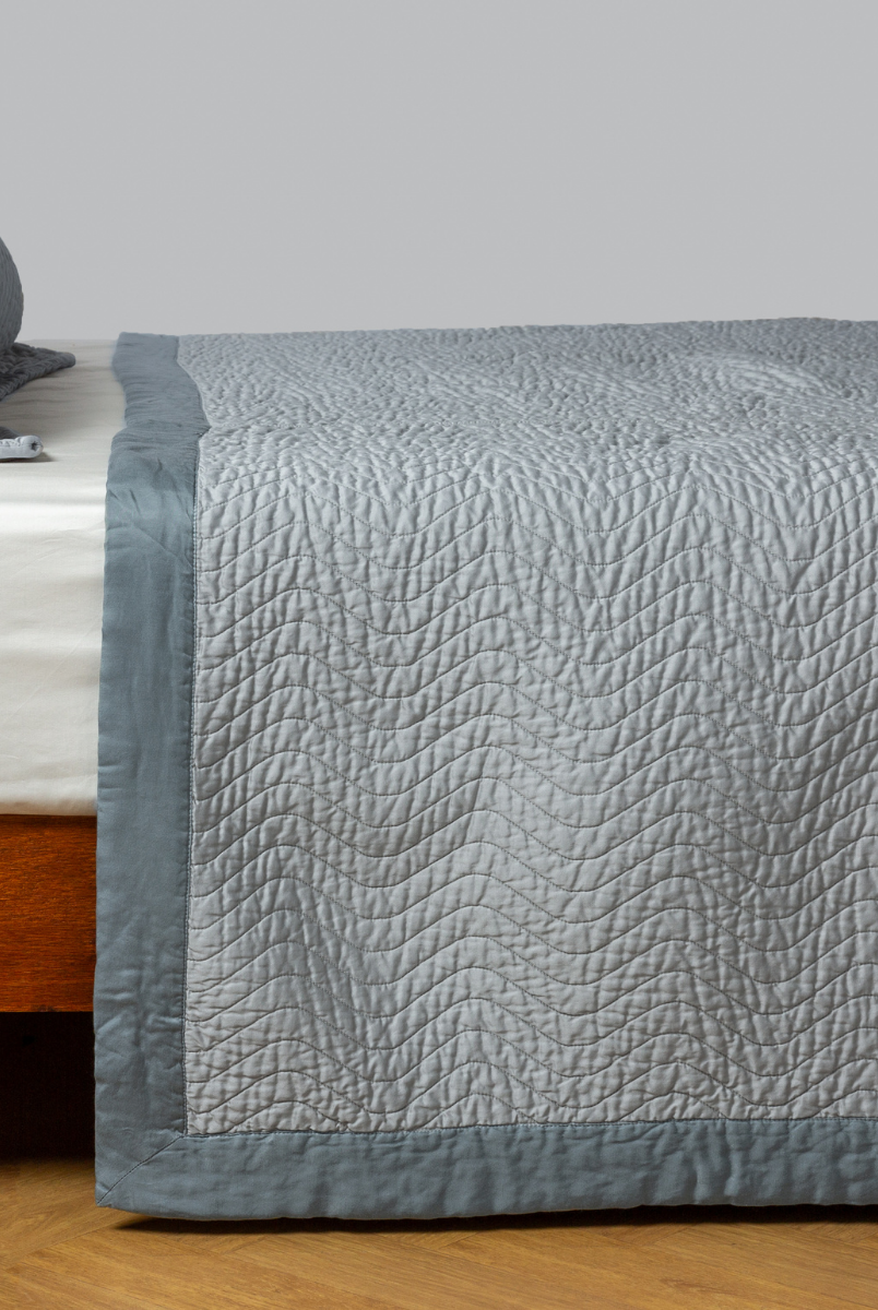 Mineral: quilted cotton sateen coverlet with matching sham on a winter white fitted sheet - side view. 