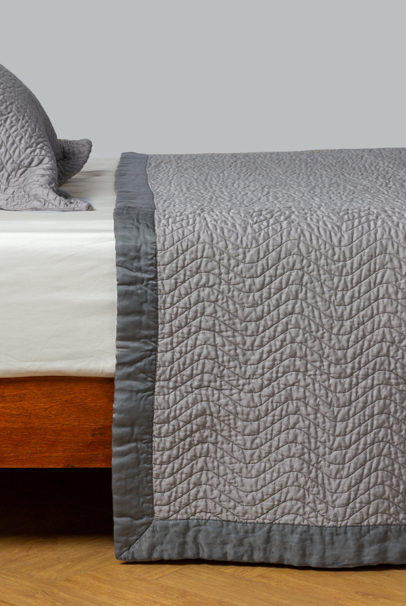 Moonlight: quilted cotton sateen coverlet with matching sham on a winter white fitted sheet - side view. 