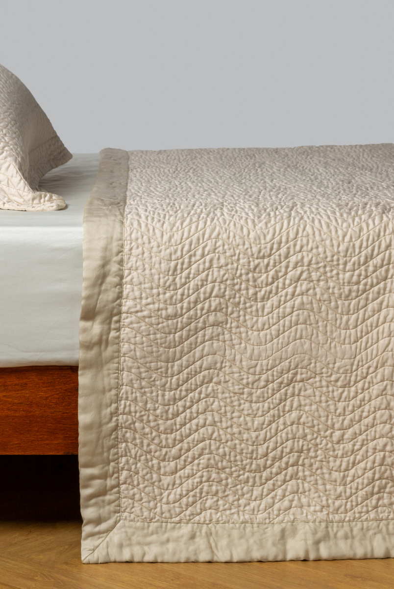 Parchment: quilted cotton sateen coverlet with matching sham on a winter white fitted sheet - side view. 