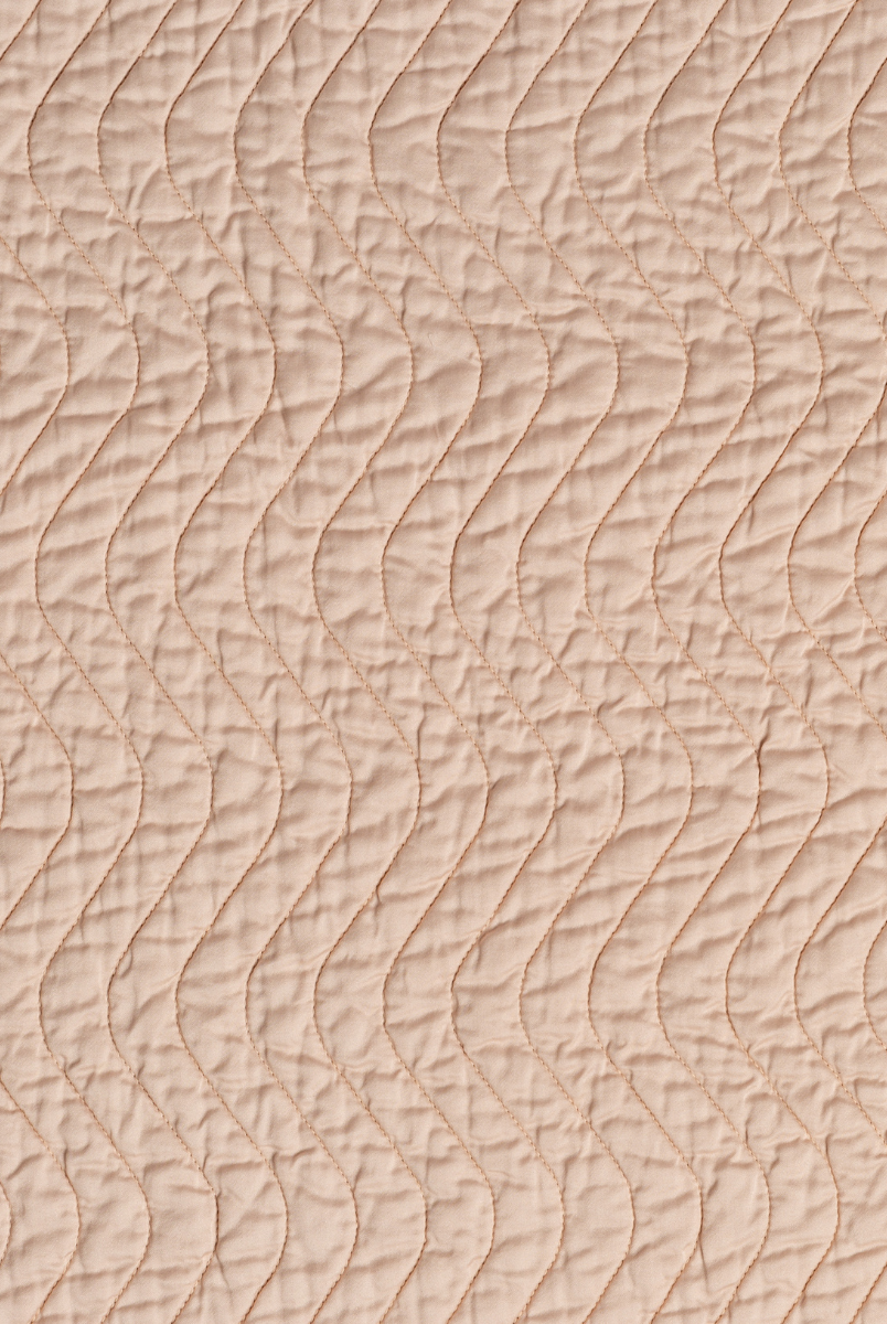Pearl: A close up of quilted cotton sateen fabric in pearl, a nude-like, soft rose pink tone.