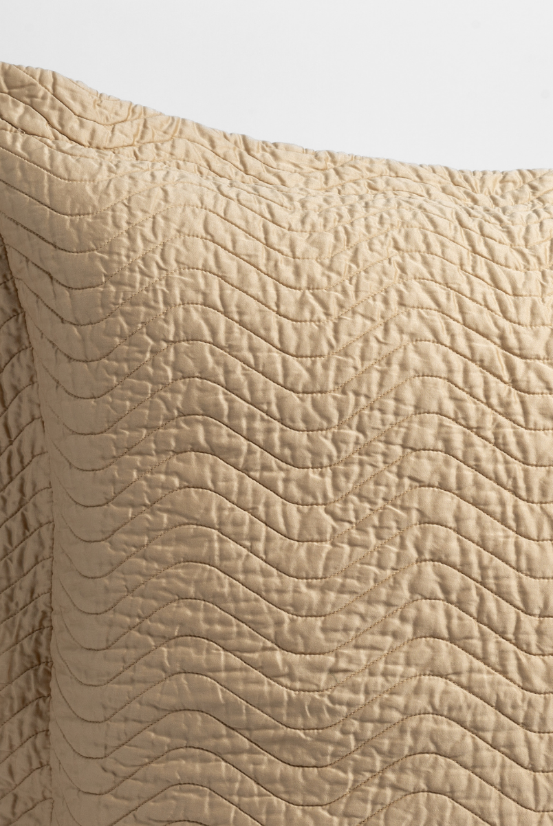 Honeycomb: close up of the corner of a quilted cotton sateen pillow sham - shot against a white background. 