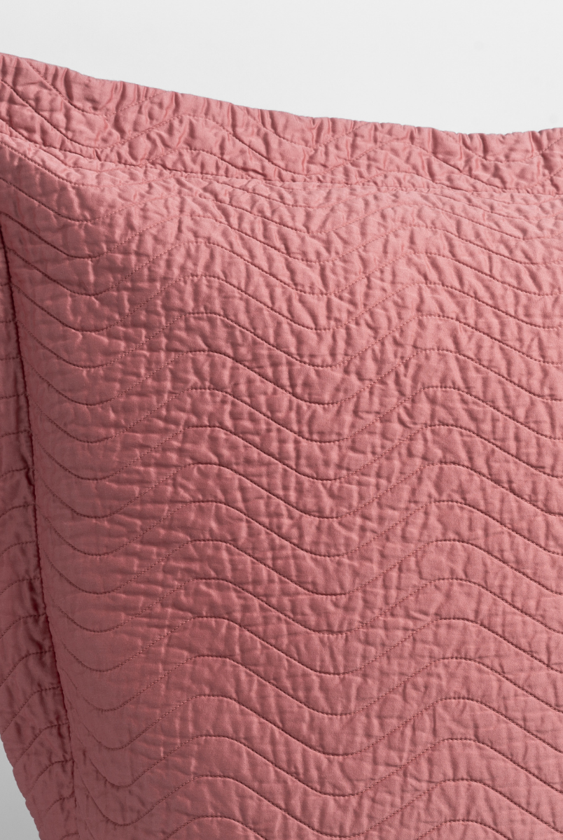 Poppy: close up of the corner of a quilted cotton sateen pillow sham - shot against a white background. 