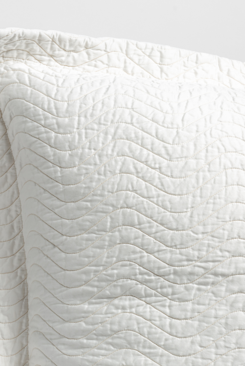 Winter White: a close up of a pillow corner showing the flange framing quilted cotton sateen shot against a white background. 